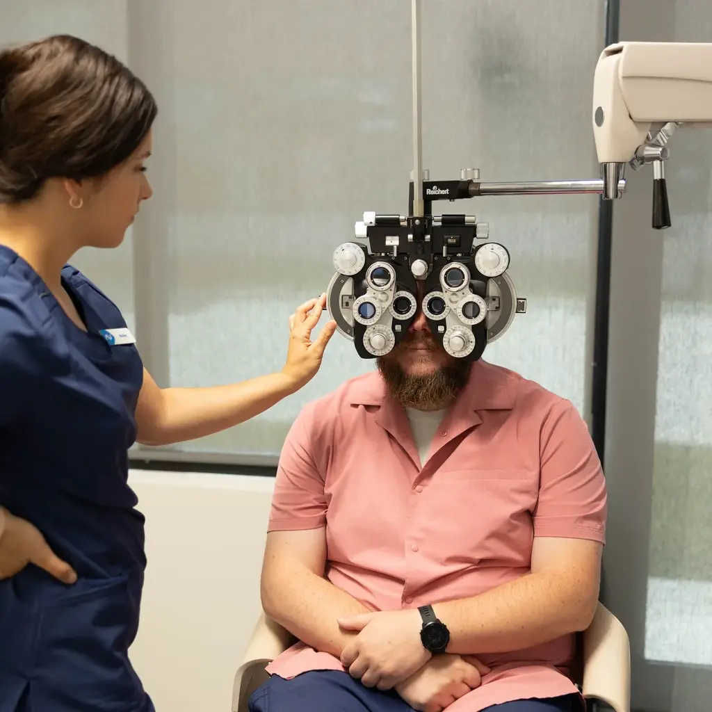Technician positioning a phoropter for a patient during refraction testing at Modern Vision Centers